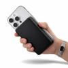 A power bank in black being held next to a smartphone, showcasing a sleek design and compact size.