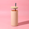 A drink bottle featuring a transparent upper section and a peachy pink outer sleeve, complete with a wooden lid and a metal straw.