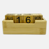A bamboo perpetual calendar with wooden blocks displaying the date and month, housed in a rectangular base.