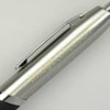 A silver pen with a black grip and a metal clip, featuring branding on the barrel.
