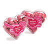 Acrylic heart container filled with pink chocolate beans, featuring a decorative heart-shaped design and a logo.