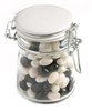 A glass clip lock jar filled with black and white jelly beans. The jar has a metal latch and a silver lid.