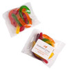 A clear plastic bag contains colourful gummy snakes in red, green, yellow, and orange hues, featuring a logo on the packaging.