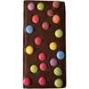 A chocolate bar with a smooth dark brown surface adorned with colourful, round candy spots in pink, blue, green, and yellow.