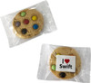A cookie featuring colourful chocolate buttons, wrapped in clear packaging with a logo.