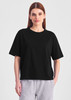 A black box tee in a relaxed fit, featuring short sleeves. The model wears it with grey bottoms.