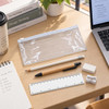 A clear stationery pouch contains a pencil, pen, eraser, ruler, and sharpener, with a notepad and laptop in the background.