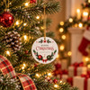 A ceramic ornament in white with festive red and green designs, hanging on a decorated Christmas tree.