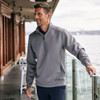 A half zip jacket in grey worn by a man, standing by a railing with a waterfront view.