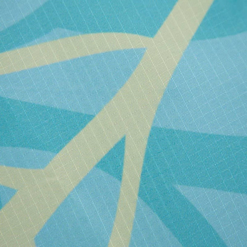 A square outdoor blanket in aqua and light cream with a textured geometric pattern, featuring a logo.