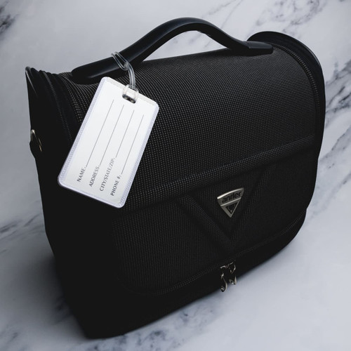 A black luggage tag attached to a stylish black bag, featuring a logo and an empty information panel.