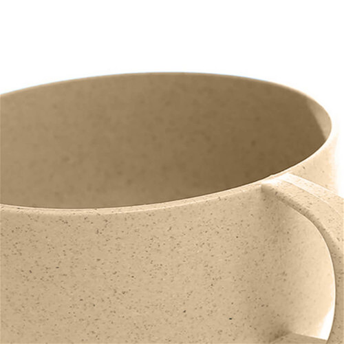 A reusable coffee cup in a light beige colour, featuring a handle and made from wheat straw material.