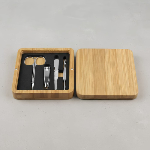 A bamboo manicure set featuring stainless steel tools, including scissors, a nail clipper, and a cuticle pusher, in a wooden box.