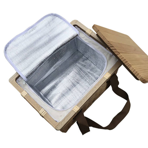 A square wicker picnic cooler basket in natural wood with a beige lid and an insulated silver interior.