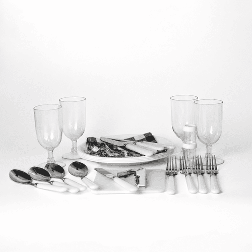 A picnic set features white-handled cutlery, glass tumblers, and serving platters on a white background.