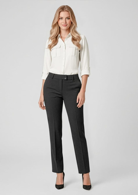 A woman wearing black slacks with a white blouse and high heels, standing against a light background. The outfit has a polished look.