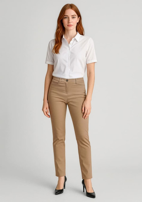 A woman stands wearing beige slim leg stretch chino pants and a white blouse, paired with black heels.