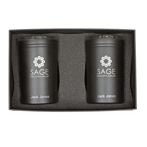 A gift box containing two black tumblers with a logo, placed in a protective foam insert.