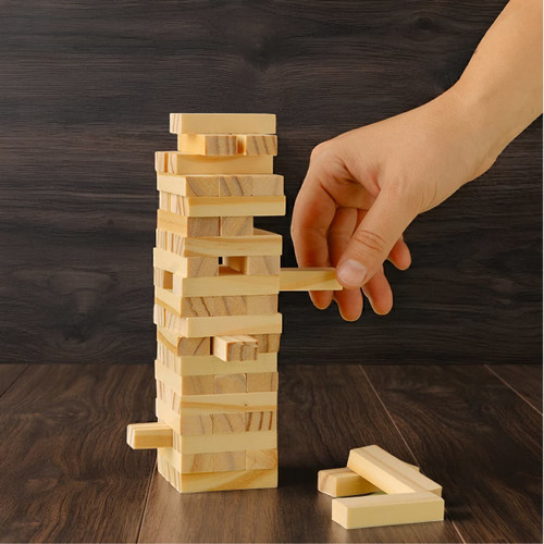 A large wooden tower set featuring light-coloured blocks stacked vertically, with a hand removing a block.