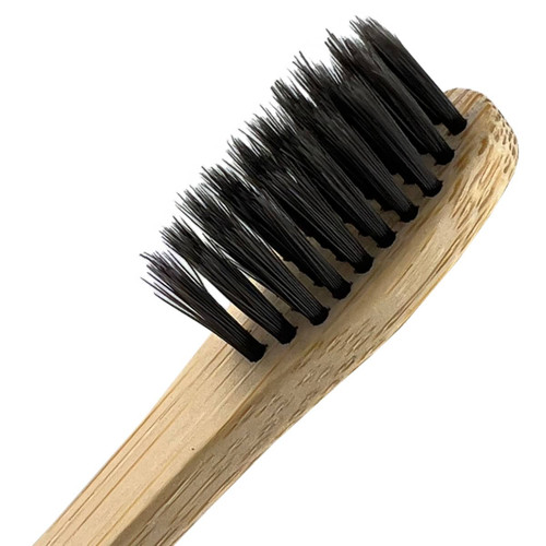 A bamboo toothbrush with a light brown handle and black bristles, featuring a simple design and natural materials.