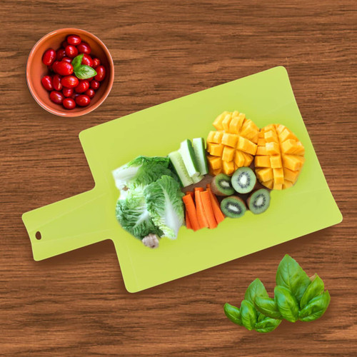A bright green foldable chopping board with chopped vegetables and fruit arranged on it, alongside a bowl of cherry tomatoes.