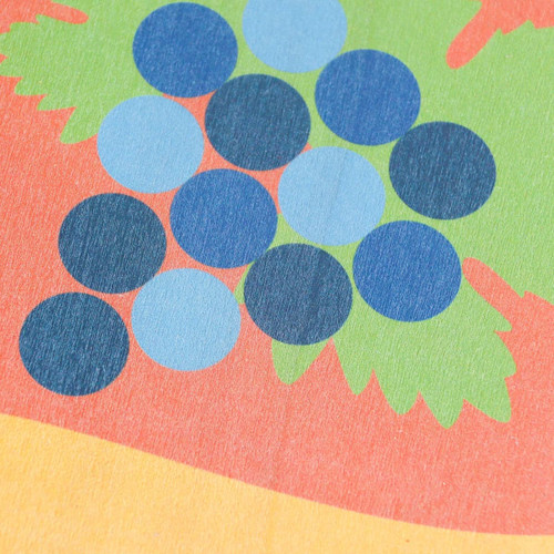 A wooden sign board featuring vibrant colours of red, green, blue, and yellow with a circular grape design.