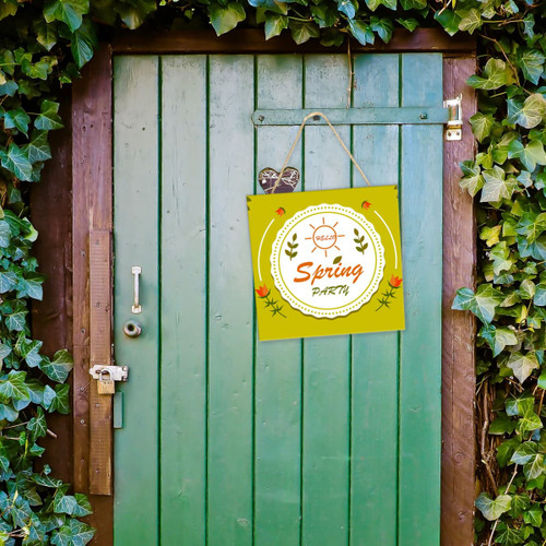 A wooden sign board in green and yellow hanging on a green door, surrounded by ivy leaves.