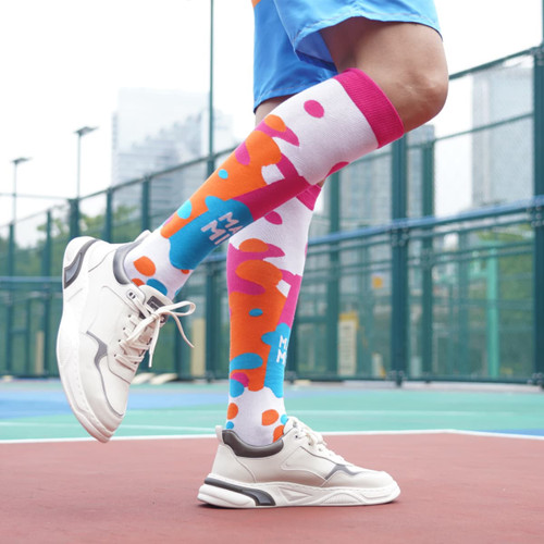 Knee high socks featuring a vibrant pattern of pink, blue, and white, paired with sporty footwear.