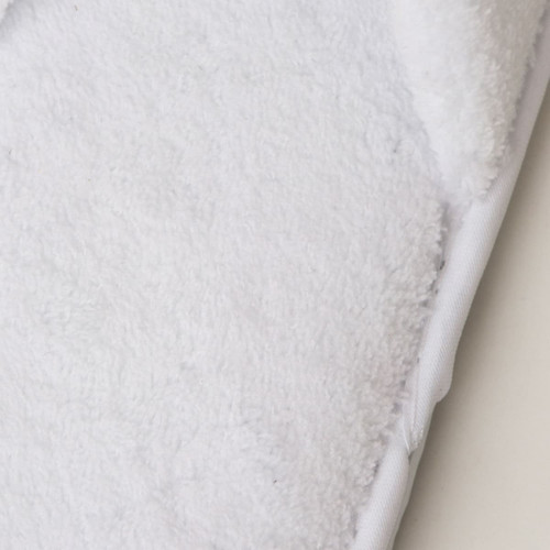 A pair of soft white hotel slippers featuring a plush texture and a branded logo on the side.