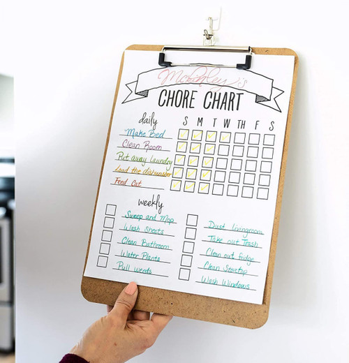 A wooden clipboard featuring a chore chart with colourful sections for daily and weekly tasks. It has a clip at the top.