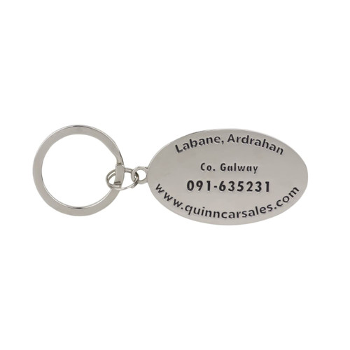 A silver oval keyring with an attached ring, featuring engraved details and a logo.