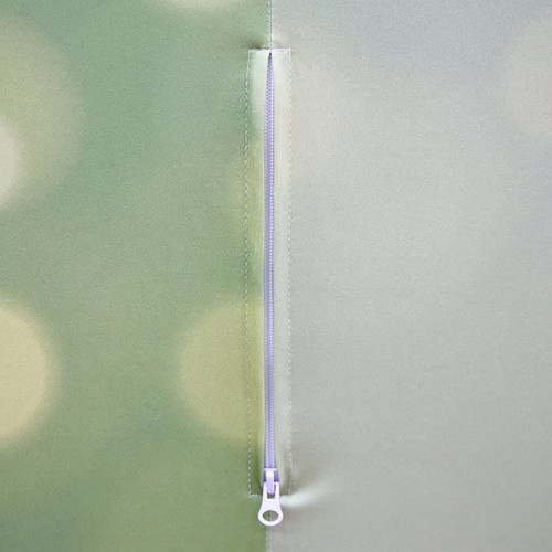 A close-up of a zipper on a fabric display counter in green tones, featuring a logo.