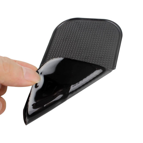 A black dashboard mat being lifted, showcasing its textured surface and flexible design.