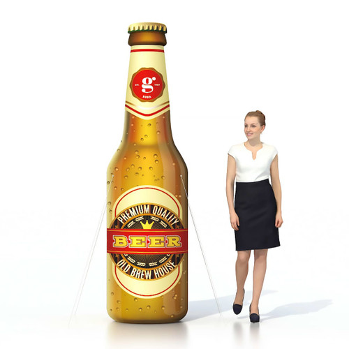 An inflatable beer bottle in brown with a label and a woman in a black skirt and white top beside it.