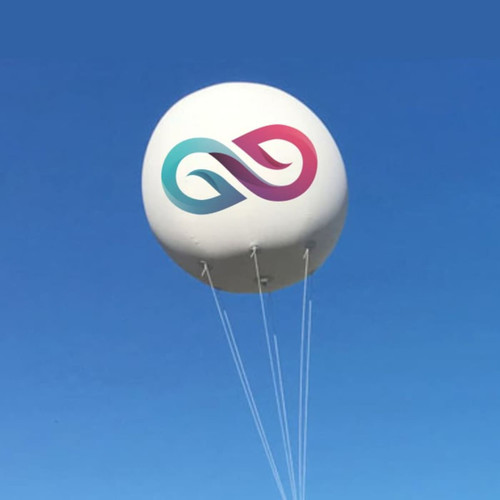 An inflatable advertising balloon in white, featuring a logo with teal and pink elements, floating against a blue sky.