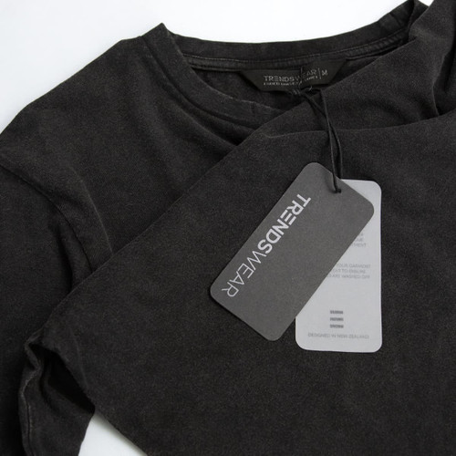 A faded black unisex T-shirt featuring a logo and a hang tag detailing care instructions.