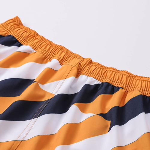 Women's board shorts in orange, navy, and white with a wavy pattern, featuring an elastic waistband and branding.