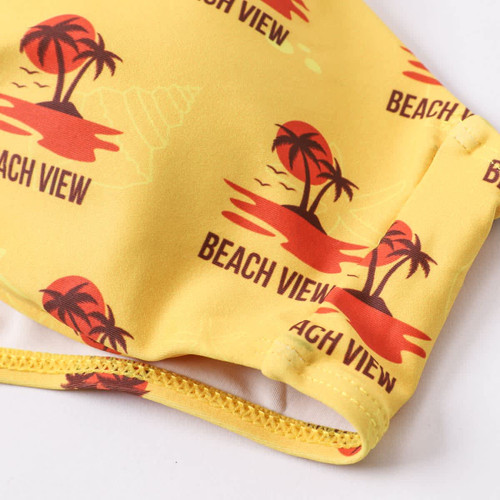 A yellow bikini top featuring a beach scene with palm trees and the phrase "BEACH VIEW," and includes a logo.