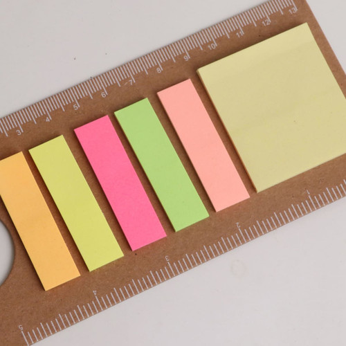 A sticky note pad featuring a ruler design, with yellow, green, pink, and peach sticky notes in various sizes.