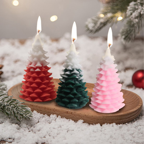 Cedar Christmas tree-shaped candles in red, green, and pink, featuring textured layers and warm flames, on a wooden tray.