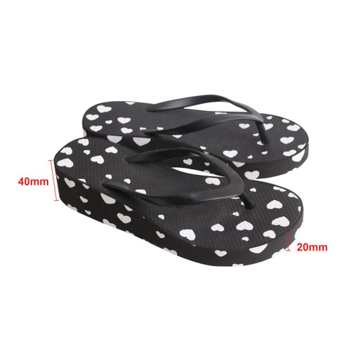 A pair of black thongs with white heart patterns, featuring a raised platform design.