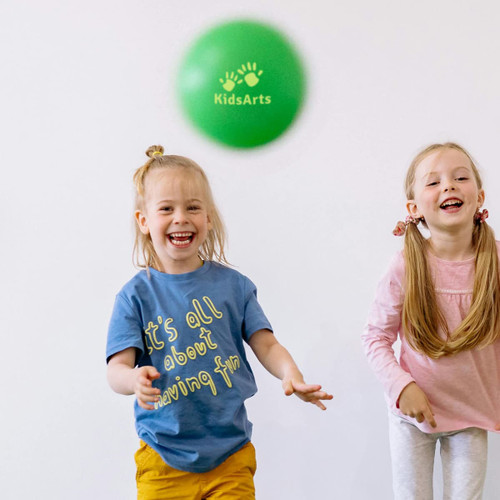 A green inflatable PVC ball mid-air, with two children smiling and playing in the background. One child wears a blue shirt, and the other wears a pink top.
