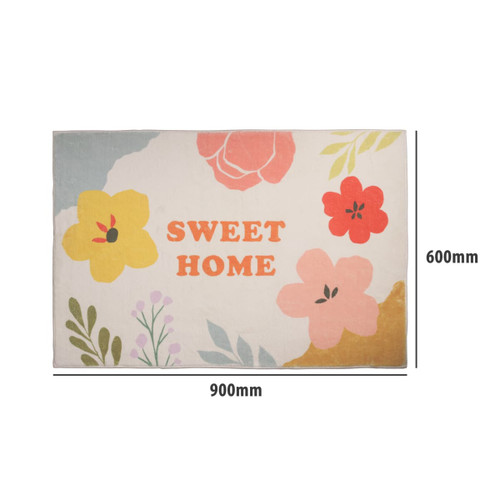 A floral plush mat in pastel colours featuring bright flowers and a central logo. Dimensions: 900mm x 600mm.