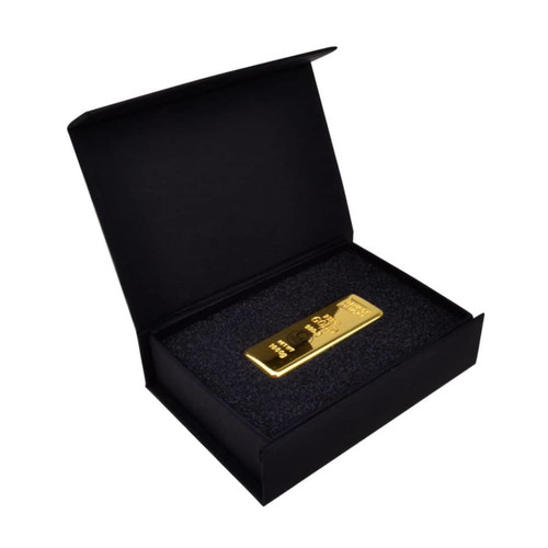 A black magnetic gift box contains a gold bar resting on black foam. The box features a subtle branding logo.