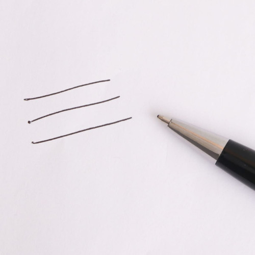 A metal pen with a sleek silver tip next to three evenly drawn black lines on a white paper background.