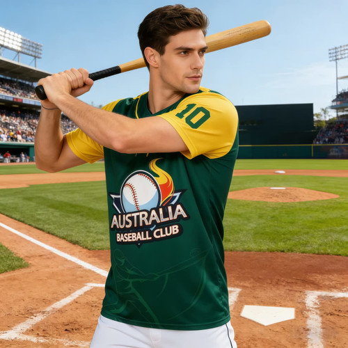 A men's 100% polyester sublimated baseball jersey in green and yellow, featuring a logo, worn by a model holding a bat.