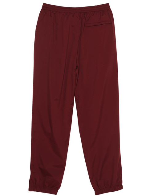 Maroon track pants with an elastic waistband and cuffed hems. Features a logo. Suitable for kids.