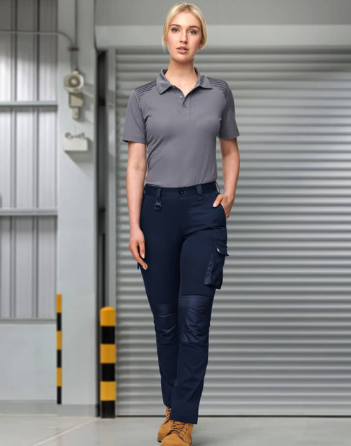 Unisex navy cargo work pants with multiple pockets, worn with a grey polo shirt. Features a logo.