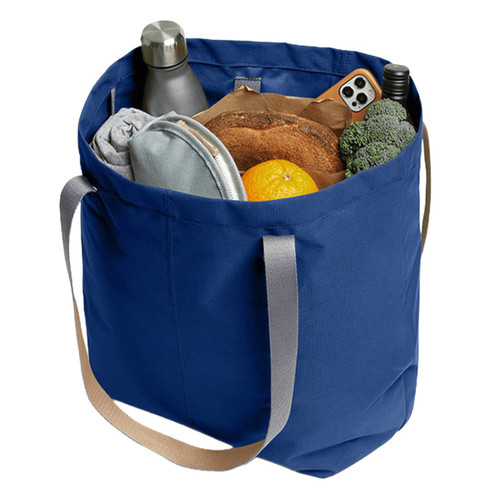 A navy blue tote bag filled with a drink bottle, food items, and a grey pouch, featuring sturdy handles.