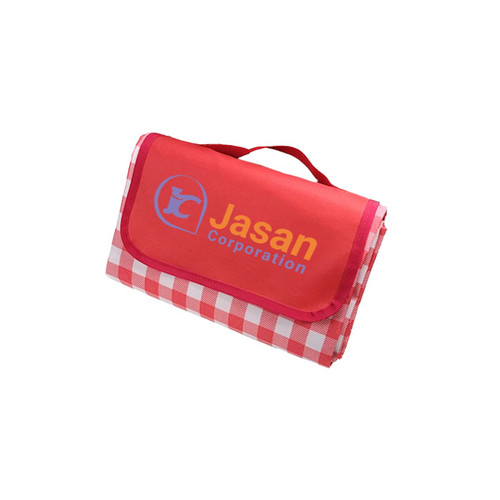 A large picnic blanket in red with a checked pattern and a logo on one side, neatly folded with a handle.